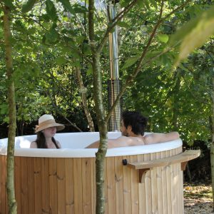 Hébergement insolite en Pays de la Loire : baignoire en bois sous les arbres.