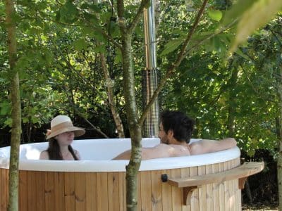 Hébergement insolite en Pays de la Loire : baignoire en bois sous les arbres.