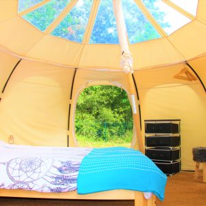 Tente géodésique lumineuse avec lit douillet et décoration bohème au Languedoc-Roussillon.