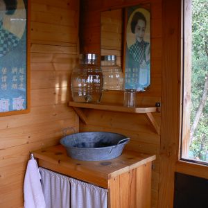 Cabane en bois avec lavabo vintage et affiches rétro, idéale pour un séjour insolite.