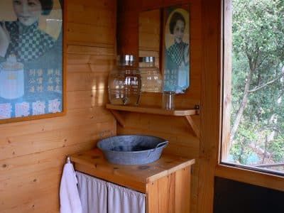 Cabane en bois avec lavabo vintage et affiches rétro, idéale pour un séjour insolite.