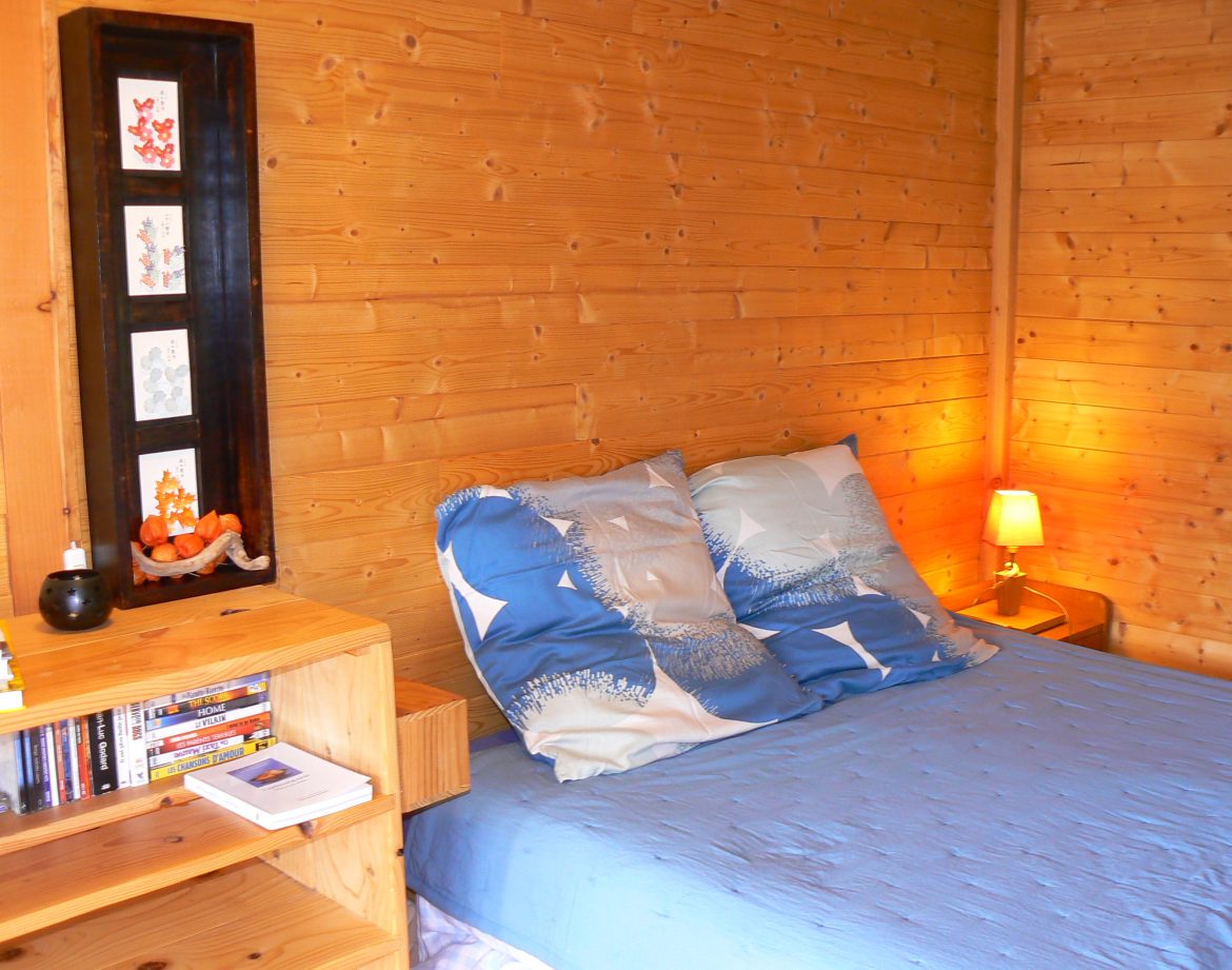 Chalet en bois chaleureux avec lit douillet et décoration apaisante.