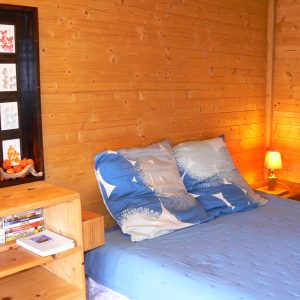 Chalet en bois chaleureux avec lit douillet et décoration apaisante.