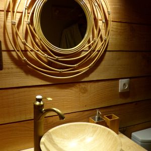 Élégant hébergement insolite avec lavabo en pierre et miroir en rotin.