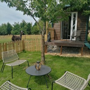 Cabane en bois dans le Pays de la Loire, avec un jardin verdoyant et des chaises confortables.