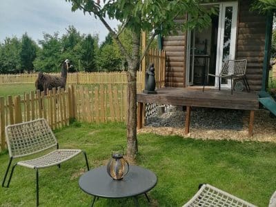 Cabane en bois dans le Pays de la Loire, avec un jardin verdoyant et des chaises confortables.