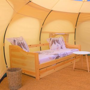 Tente glamping au Languedoc-Roussillon, avec un lit en bois et décor floral.