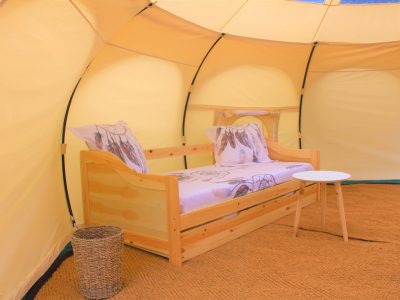 Tente glamping au Languedoc-Roussillon, avec un lit en bois et décor floral.