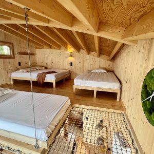 Hébergement insolite en bois avec lits suspendus et décoration naturelle.