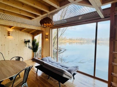 Cabane moderne en bois avec vue panoramique sur un lac paisible en Auvergne-Rhône-Alpes.