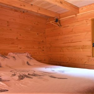 Cabane en bois dans le Languedoc-Roussillon, lit douillet avec draps décorés.