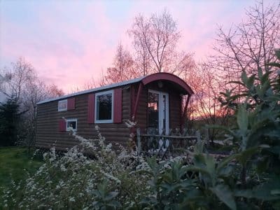 Cabane en bois dans le Pays de la Loire, sous un ciel rose au coucher du soleil.