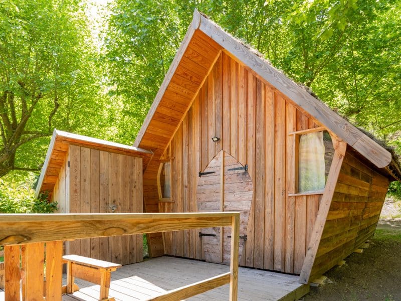 Cabane en bois au milieu des arbres, offrant un cadre naturel apaisant.