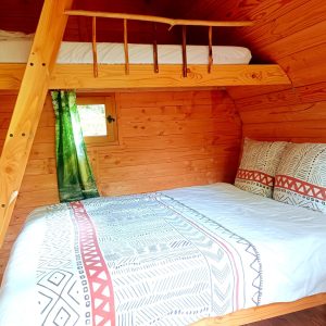 Cabane en bois cosy avec lit double et mezzanine, ambiance chaleureuse et naturelle.