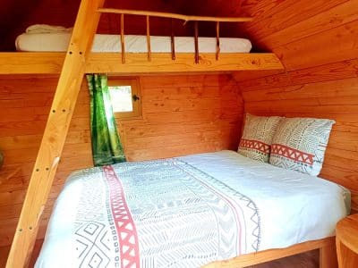 Cabane en bois cosy avec lit double et mezzanine, ambiance chaleureuse et naturelle.