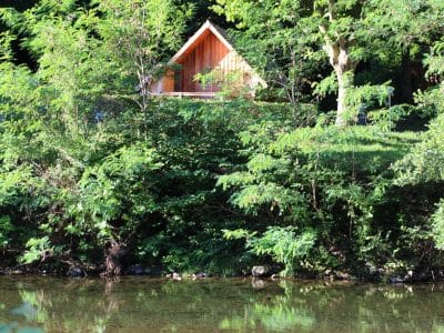 Cabane en bois au bord de leau, entourée de verdure luxuriante à Languedoc-Roussillon.