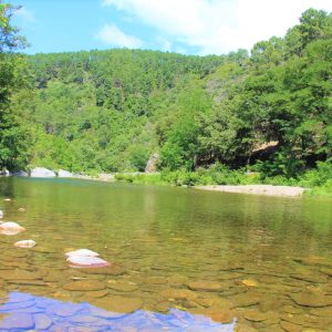 Hébergement insolite en pleine nature, au bord dune rivière entourée de verdure.
