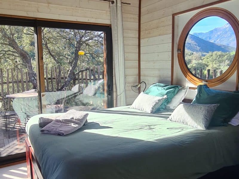 Chalet cosy avec vue panoramique, lit douillet et décoration en bois chaleureux.