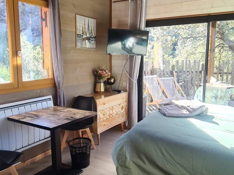 Chalet cosy avec vue, lit confortable et coin repas lumineux.