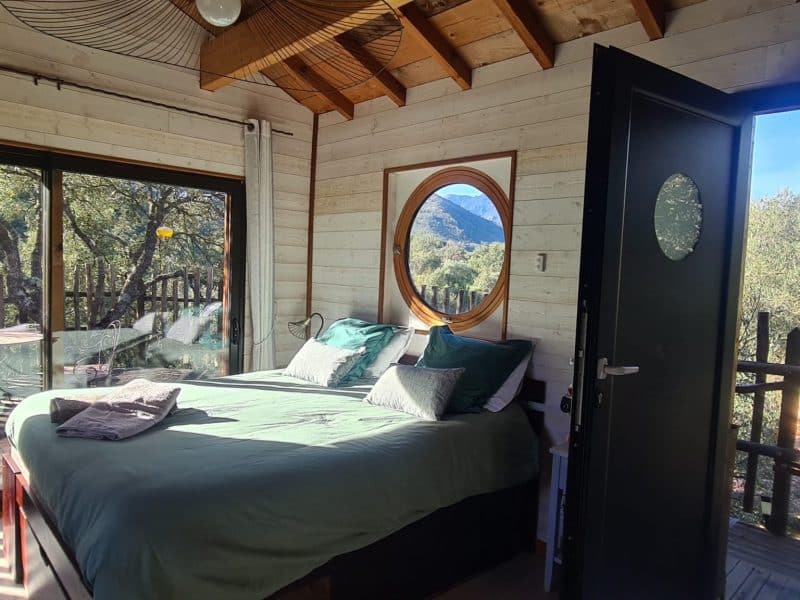 Chalet moderne avec vue sur la montagne, lit confortable et grandes fenêtres.