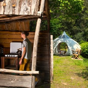 Hébergement insolite en Languedoc-Roussillon : cabane en bois avec cuisine extérieure et tipi.