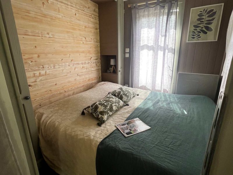 Chambre cosy avec lit double, murs en bois et lumière naturelle. Parfait pour un séjour relaxant.