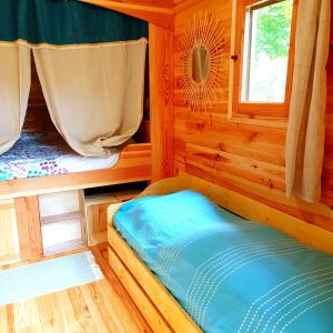 Cabane en bois chaleureuse avec lits simples et décor naturel apaisant.