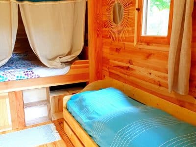 Cabane en bois chaleureuse avec lits simples et décor naturel apaisant.