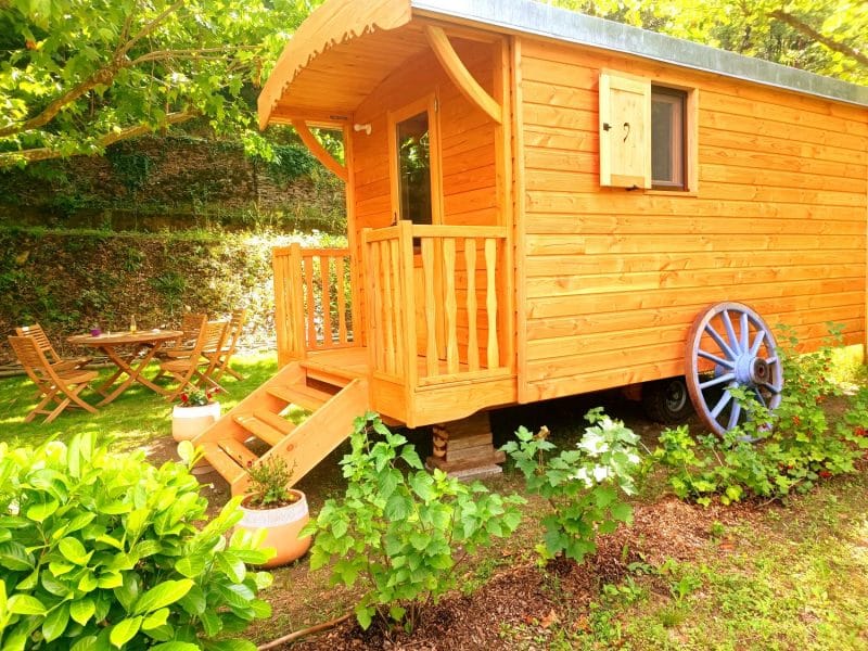 Charmante roulotte en bois, nichée dans un jardin verdoyant avec terrasse en bois.