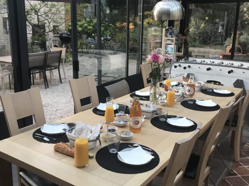 Salle à manger lumineuse dans un gîte, avec une grande table et vue sur le jardin.