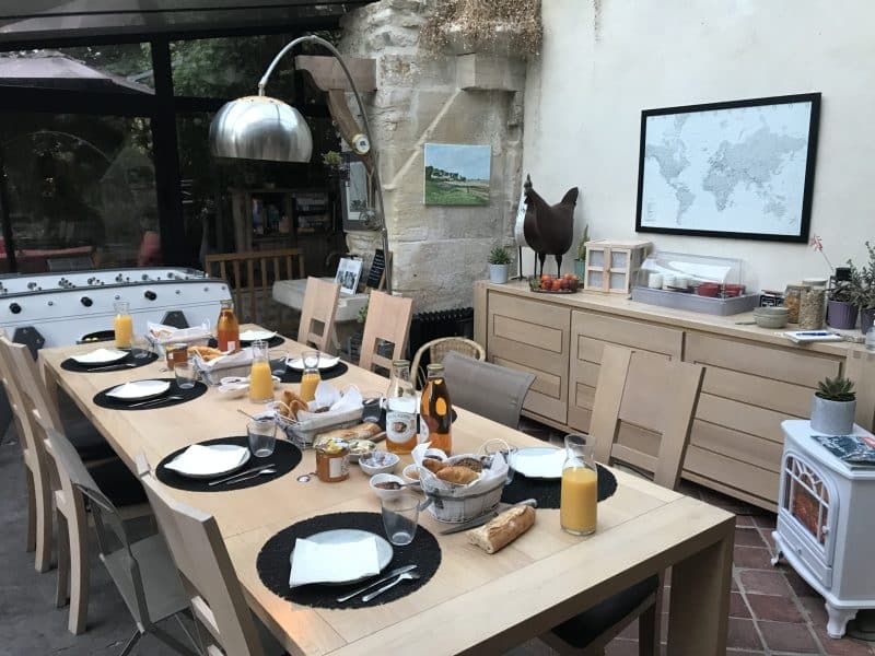 Chambre dhôtes avec salle à manger lumineuse, décorée de plantes et dune grande table.