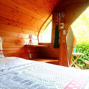 Cabane en bois avec intérieur chaleureux et vue sur la nature verdoyante.