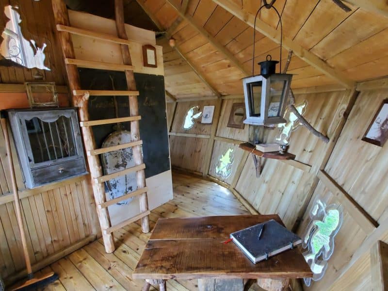 Cabane en bois avec échelle, intérieur chaleureux et décor rustique.