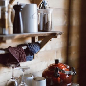 Intérieur dun chalet en bois en Auvergne, avec une bouilloire rouge et des ustensiles.