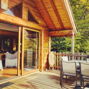 Chalet en bois avec terrasse ensoleillée, idéal pour un séjour en Auvergne-Rhône-Alpes.