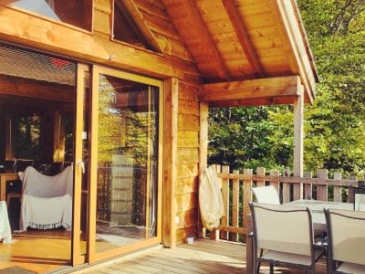 Chalet en bois avec terrasse ensoleillée, idéal pour un séjour en Auvergne-Rhône-Alpes.