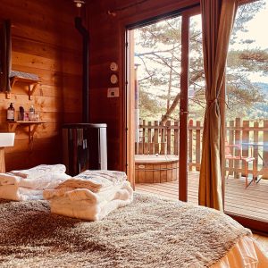 Chalet en bois avec vue, lit douillet et accès à un jacuzzi extérieur.