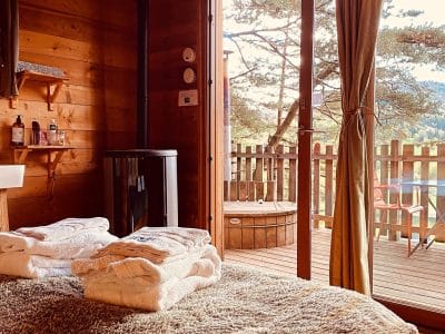 Chalet en bois avec vue, lit douillet et accès à un jacuzzi extérieur.