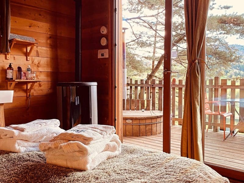 Chalet en bois chaleureux avec vue sur la nature et jacuzzi extérieur.
