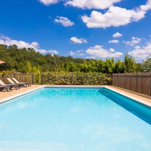 Hébergement insolite en Aquitaine avec piscine et chaises longues sous un ciel ensoleillé.