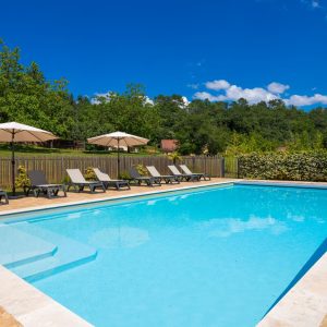Hébergement insolite en Aquitaine avec piscine et chaises longues sous parasols.