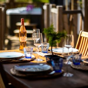 Table en bois dressée pour un repas, avec une bouteille de rosé, en hébergement insolite.