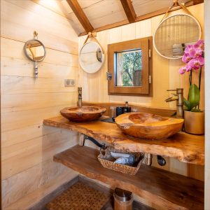 Salle de bain en bois dans un hébergement insolite en Aquitaine, avec lavabos en bois.