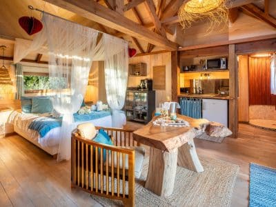 Cabane en bois avec lit douillet, décor chaleureux et cuisine intégrée.