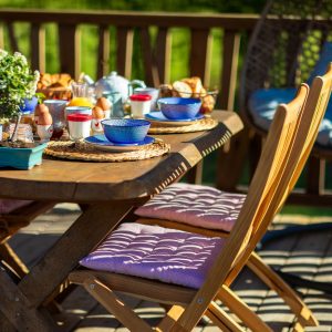 Hébergement insolite en Aquitaine : table en bois dressée avec vaisselle colorée et vue verdoyante.