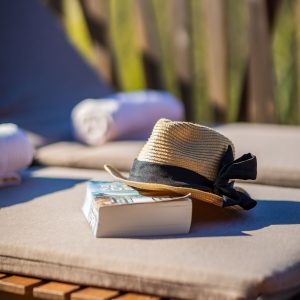 Hébergement insolite en Aquitaine : chapeau de paille et livre sur une chaise longue.
