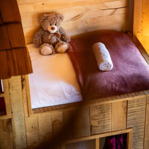 Cabane en bois avec lit douillet et ours en peluche sur la couette.