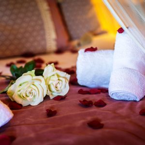 Chambre romantique en Aquitaine, décorée de pétales de rose et serviettes blanches.