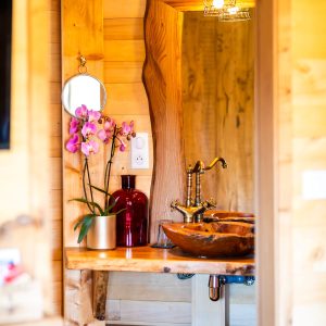 Cabane en bois en Aquitaine avec un lavabo en bois et des fleurs dorchidées.