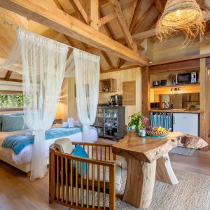 Cabane en bois avec lit à baldaquin et décor naturel, ambiance chaleureuse.